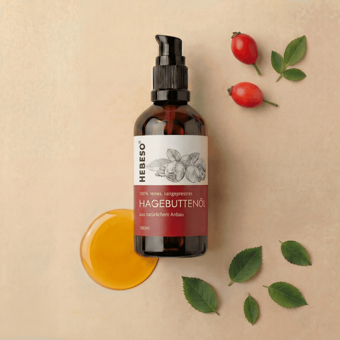 HEBESO Hagebuttenöl 100 ml mit Ölprobe, Hagebutten und grünen Blättern.