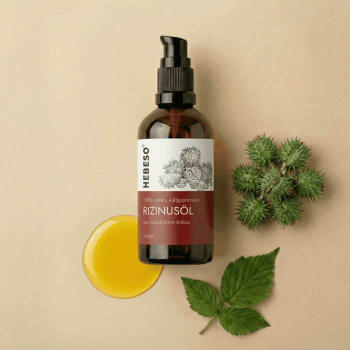 HEBESO Rizinusöl 100 ml mit gelber Ölprobe, Rizinusfrüchten und Blättern.